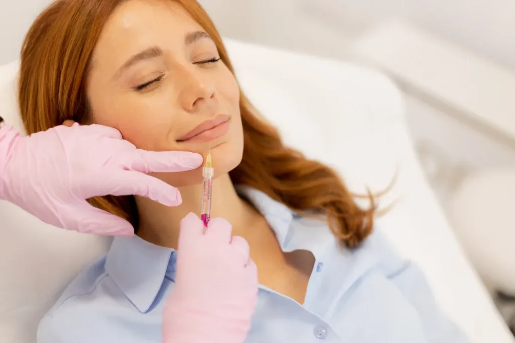A woman receiving a Juvederm lip filler injection in a professional clinic setting, highlighting a non-surgical cosmetic procedure for fuller, natural-looking lips in Novi, Michigan.