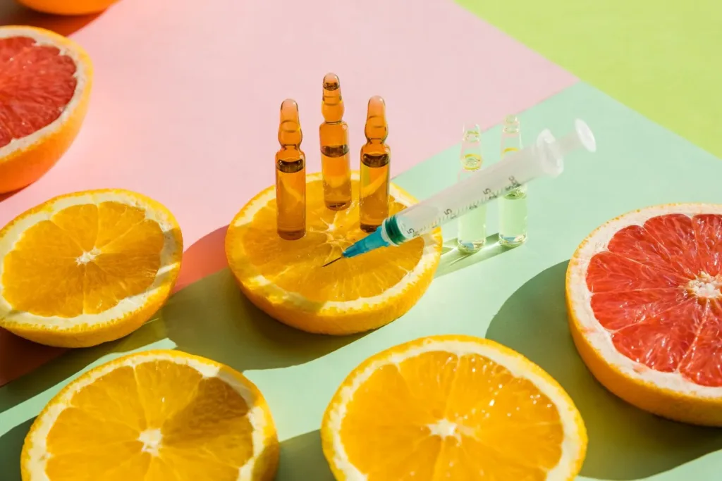 Assorted citrus fruits with medical ampoules and a syringe placed on orange slices, symbolizing natural health boosters and wellness treatments, representing Vitamin Injections in Novi for energy, immunity, and skin rejuvenation.