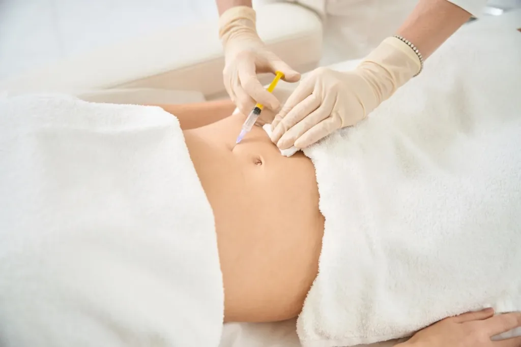 A wellness professional administering a lipo mino mix injection into a patient's abdomen at a spa clinic, highlighting a common method of delivering lipotropic injections for fat metabolism and energy boost in Novi, Michigan.