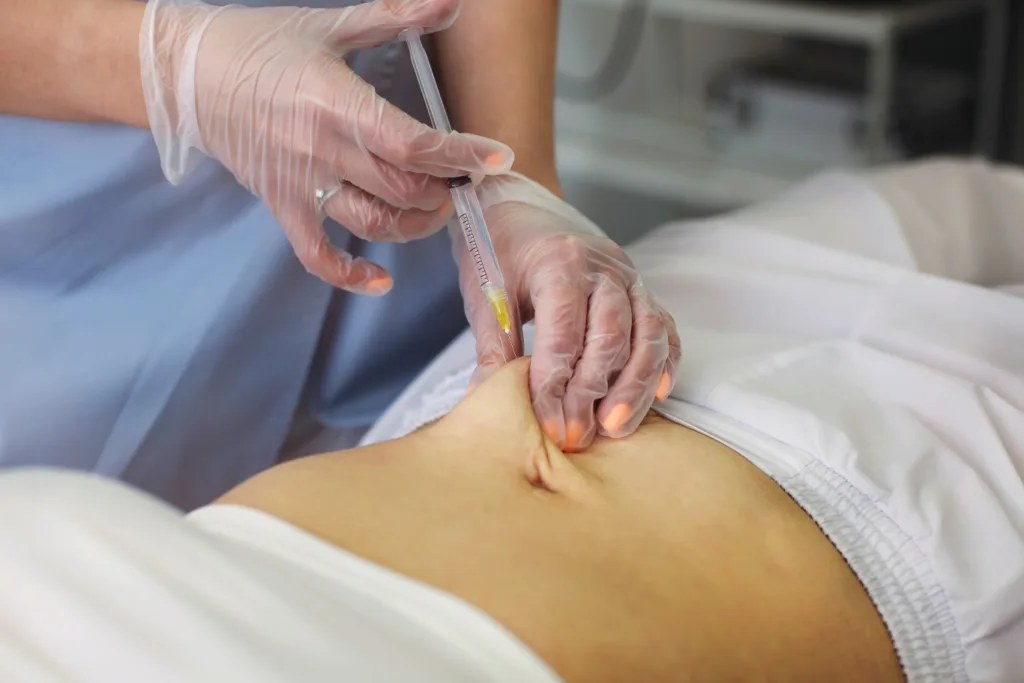 A medical professional administering a Lipo Mino Mix injection into a patient’s abdominal area during a wellness treatment.