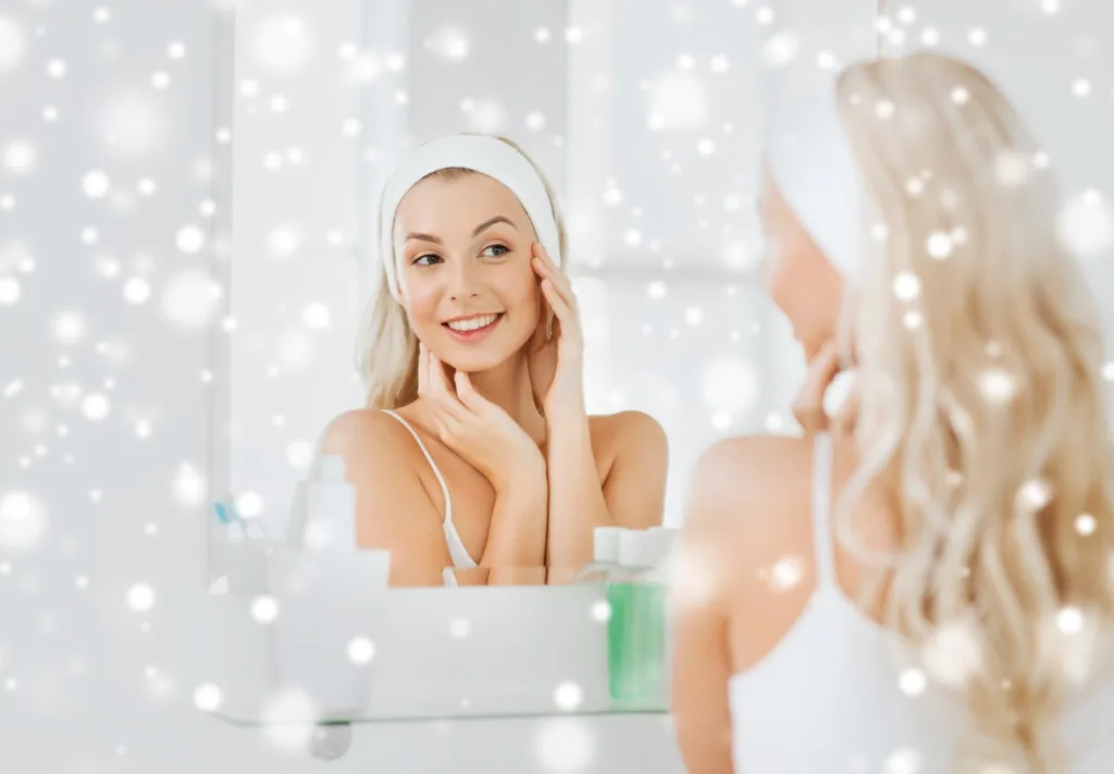 Woman applying moisturizer in front of a mirror as part of her skincare routine for winter, maintaining healthy and glowing skin during the cold season.
