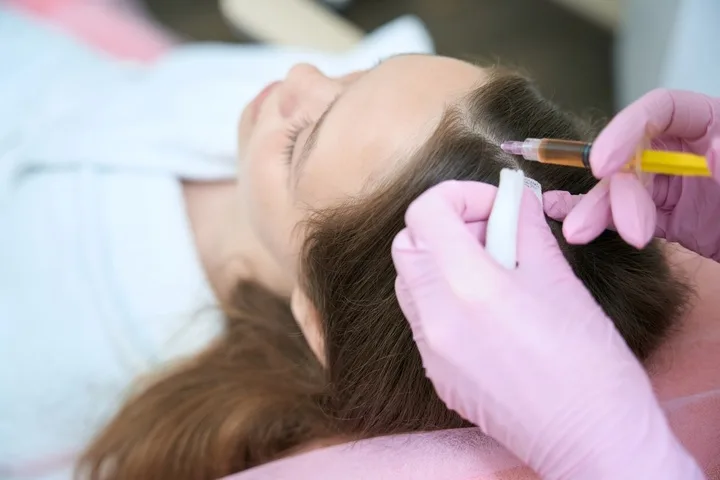 A woman receiving a professional hair restoration injection as part of a hair loss treatment in Novi,