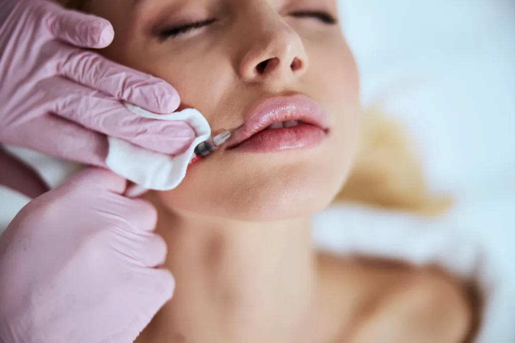 A woman receiving professional lip enhancement treatment with a precise injection, representing the kind of results someone might look for when searching for lip injections near me.